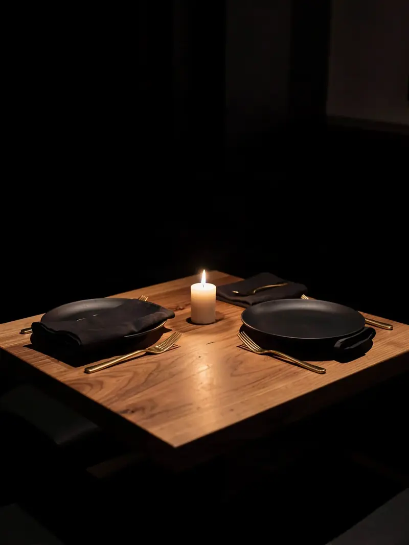 A table for two set with dark plates and a candle